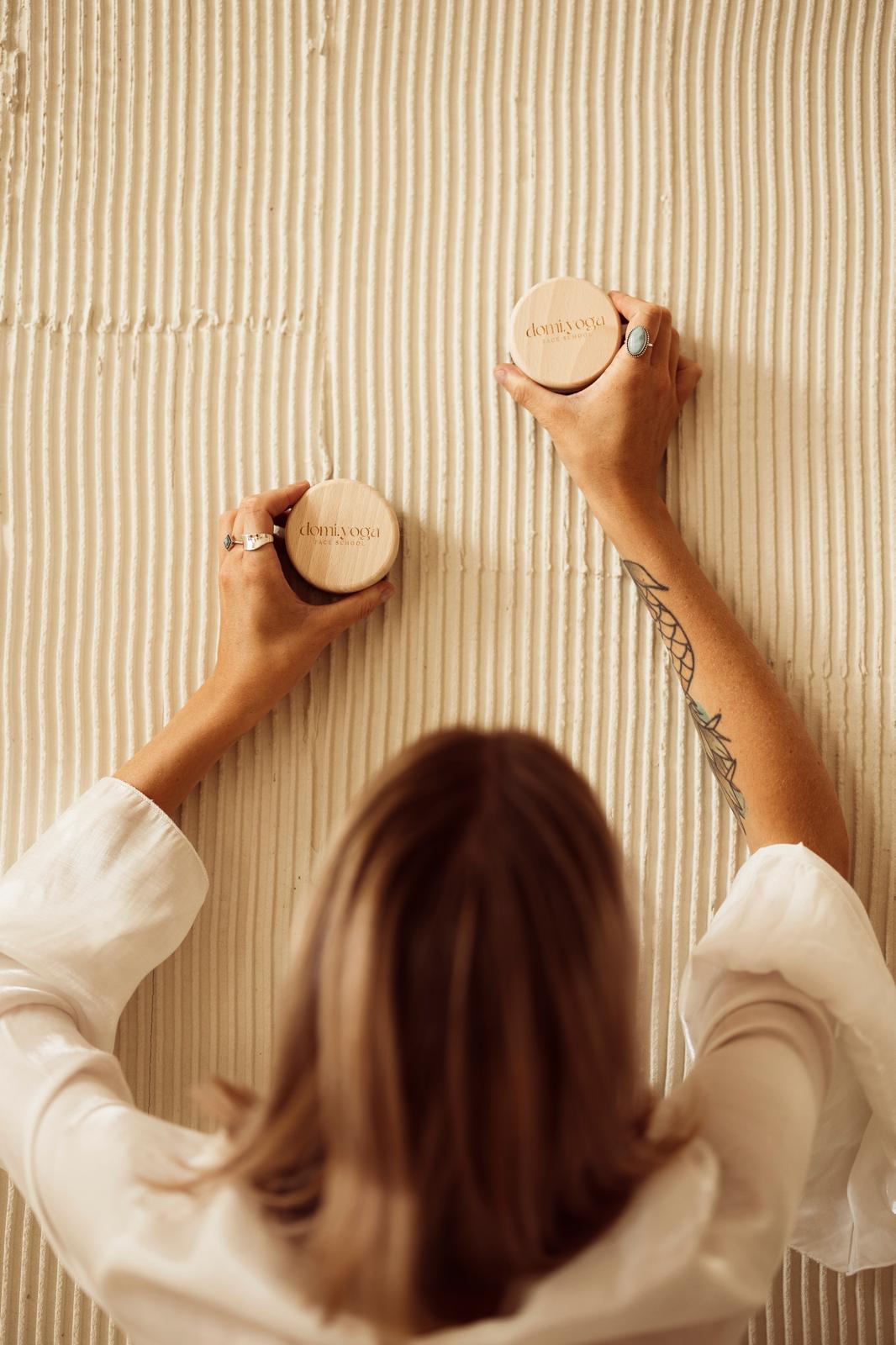 Drewniane krążki domi.yoga Face School trzymane przy ścianie
